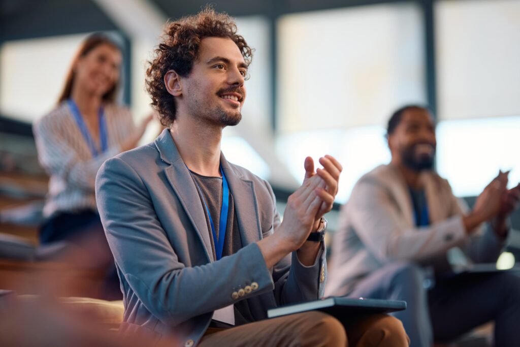 Un jeune entrepreneur applaudissant lors d'une présentation réussie dans une conférence professionnelle.