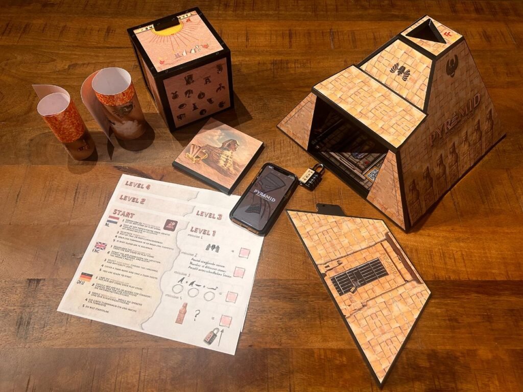 Unassembled components of the Pyramid Escape Box game at EuroParcs, including the pyramid structure, puzzle elements, game instructions, and the Pyramid XR app.