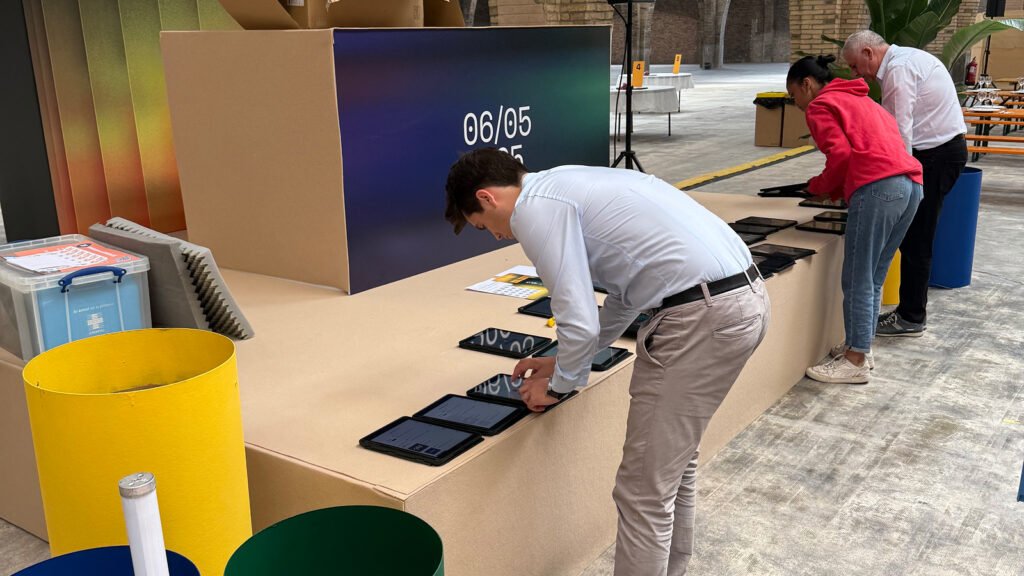 Event staff arranging Mooveteam tablets on a platform in a spacious indoor venue, preparing for a GPS-and-AR team-building activity.