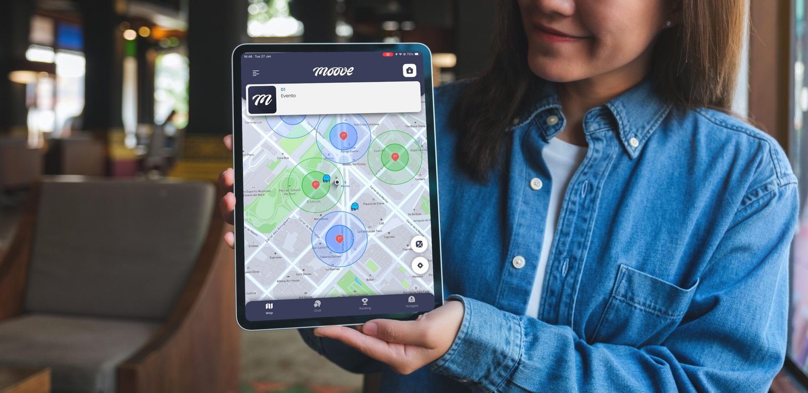 Person holding a tablet showing MooveXR app with map interface and multiple territories for a team-building game